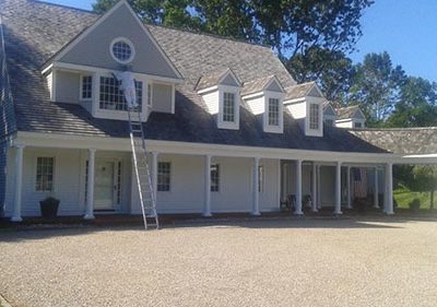 a main on a ladder painting the trim of a house